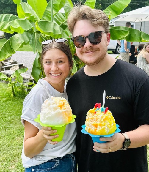 A couple with tall shave ice cups, one topped with birthday candles
